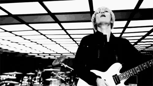 a black and white photo of a man playing a white guitar