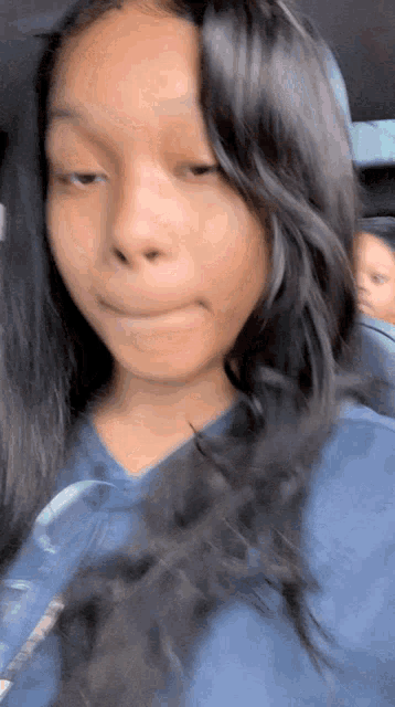 a girl in a blue shirt is making a funny face
