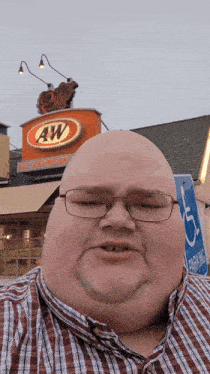 a bald man wearing glasses is standing in front of a aw restaurant