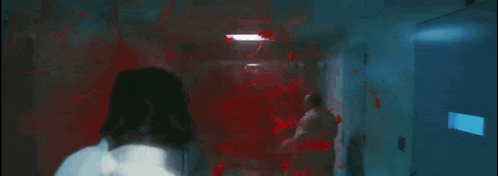 a man with blood on his face is walking down a hallway with a sign that says omg on it