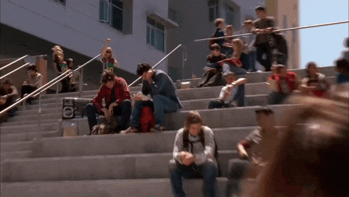 a group of people are sitting on a set of stairs in front of a building