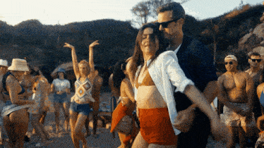a group of people are dancing on the beach