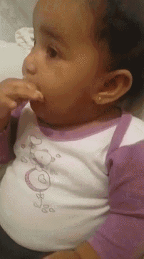 a baby in a purple and white shirt with hearts on it is eating something
