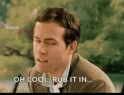 a man in a suit and tie is sitting on a bench and saying oh cool rub it in .