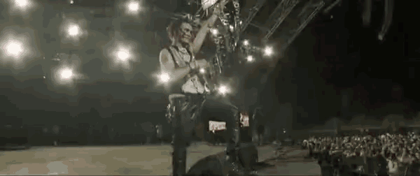 a man playing a guitar in front of a crowd with a sign that says ' slayer ' on it