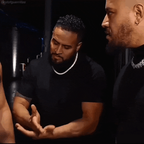 a man in a black shirt is talking to another man in a black shirt