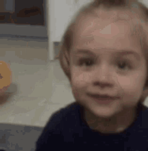 a little girl is smiling and looking at the camera while holding a toy .