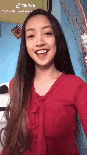 a woman in a red shirt is smiling and taking a selfie with her phone .