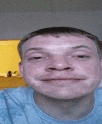 a man in a blue shirt is eating something with a spoon in his mouth