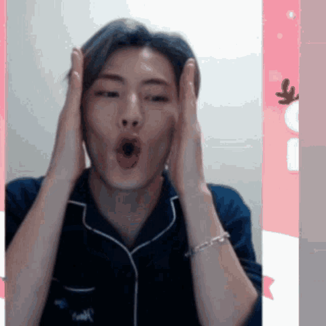 a man is making a funny face with his hands on his face .