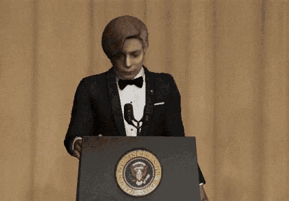 a man in a tuxedo is standing at a podium with the seal of the president of the united states on it