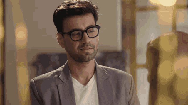 a man with glasses and a beard is wearing a suit and a white shirt