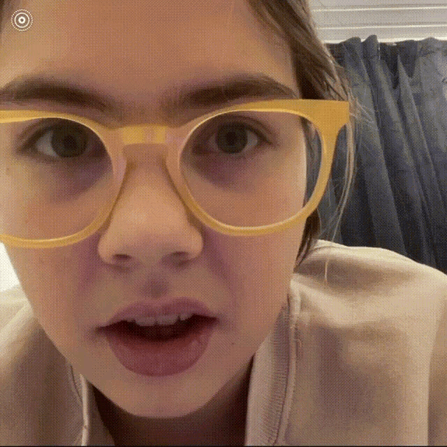 a close up of a person wearing glasses with a target in the background