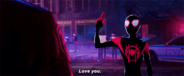 a man in a spider-man suit is standing in front of a police car and saying love you .