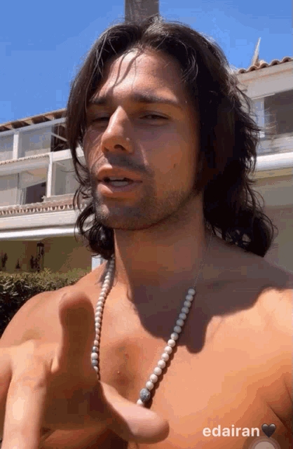 a shirtless man wearing a pearl necklace has the name edairan on the bottom right