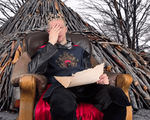 a man with a crown on his head is sitting in a chair