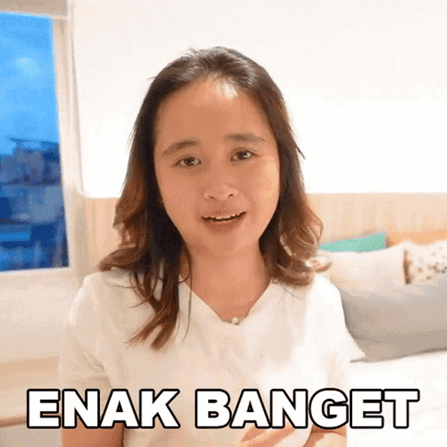 a woman in a white shirt says " enak banget " in a bedroom