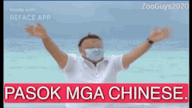 a man wearing a face mask is standing in front of the ocean