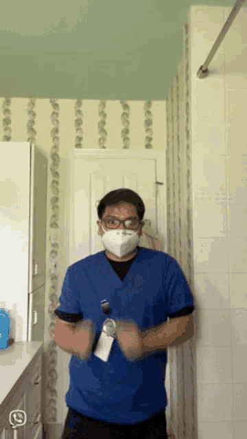 a man wearing a blue scrub top and a face mask