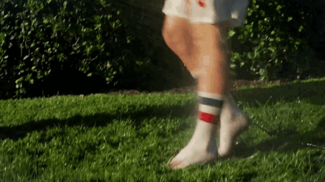 a person wearing striped socks is walking on a lush green field