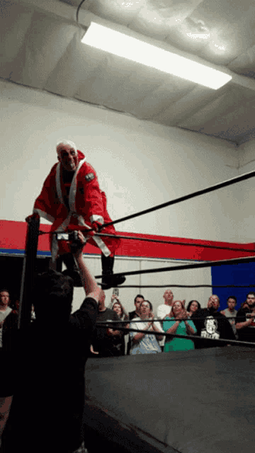 a wrestler in a santa suit is standing in a ring