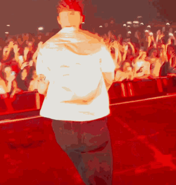 a man in a white shirt is standing on a stage in front of a crowd