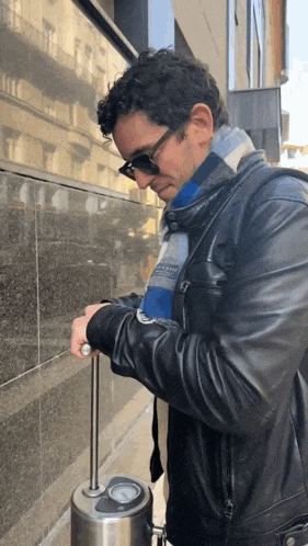a man wearing a black leather jacket and a scarf is adjusting a valve