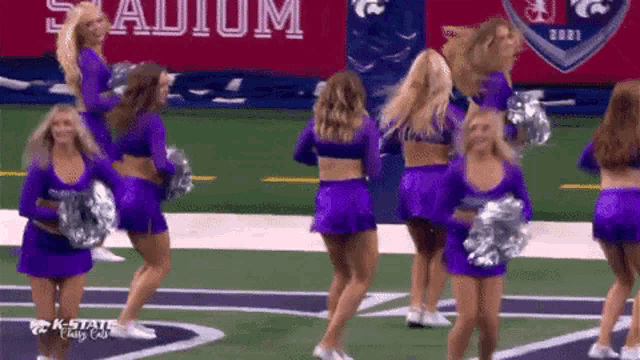 a group of cheerleaders are dancing on a field with a k-state logo in the background