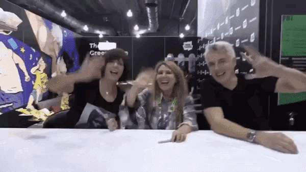 a group of people are sitting at a table with their arms outstretched