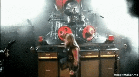 a woman is standing on a stage in front of a drum set and a guitar .