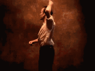 a man in a white shirt is dancing in a dark room