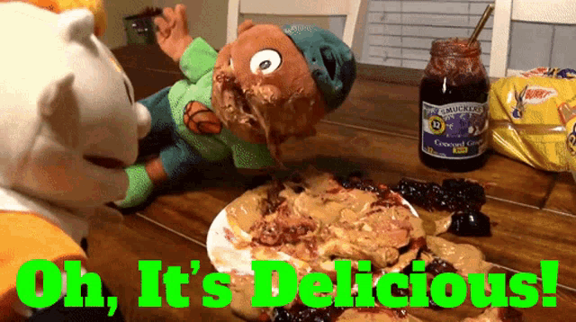 two stuffed animals are sitting at a table with a jar of blueberry jam on it