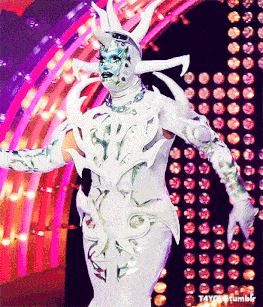 a person in a white costume is standing in front of a pink and purple wall