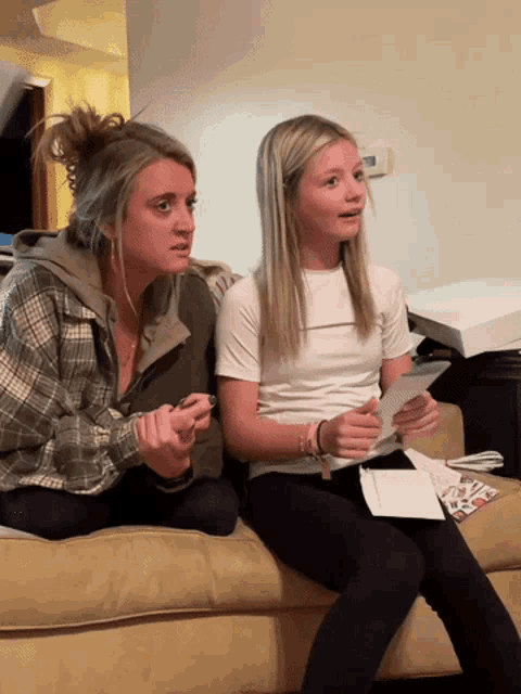 two girls are sitting on a couch looking at a card that says ' i love you '