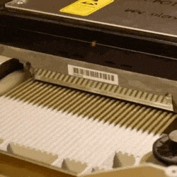 a machine is cutting a piece of paper into a row of cigarettes .