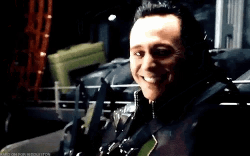 a man is smiling in a dark room while holding a gun .