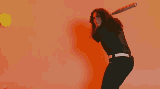 a woman in a black shirt is dancing in front of a red wall