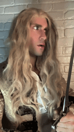 a man with very long blonde hair is holding a sword