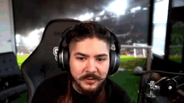 a man with a beard and mustache is wearing headphones and looking at the camera .