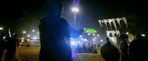 a man is holding a bottle of green liquid in front of a crowd of people