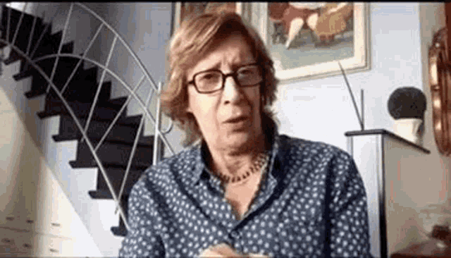 a woman wearing glasses and a necklace is sitting at a table in a living room .