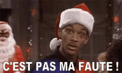 a man wearing a santa hat is standing in front of santa claus and says `` c 'est pas ma faute '' .