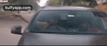 a man is driving a car down a road with his arms outstretched .