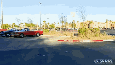 a red mustang is parked on the side of the road next to a no parking sign
