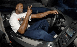 a man with a tattoo on his arm is sitting in the driver 's seat of a car