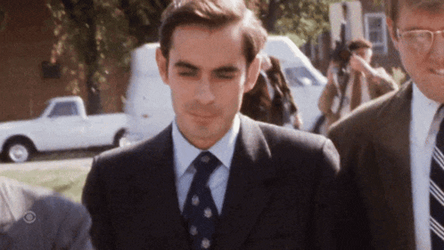 a man in a suit and tie is smiling while walking down the street
