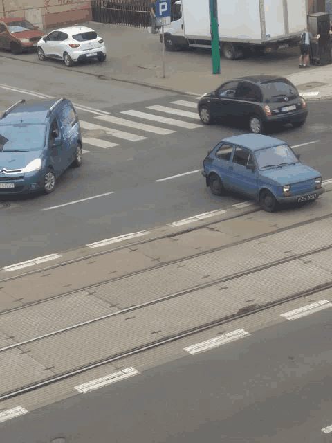 a blue car is parked on the side of the road near a sign that has the letter p on it