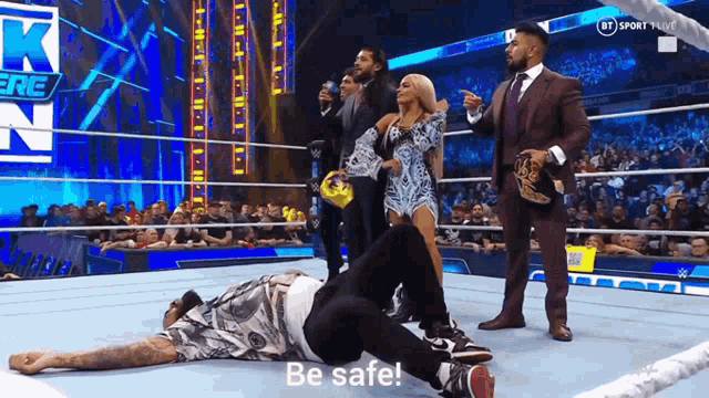 a man is laying on the ground in a wrestling ring and a woman says be safe .