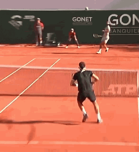 a man is playing tennis on a court with a sign that says gonet in the background