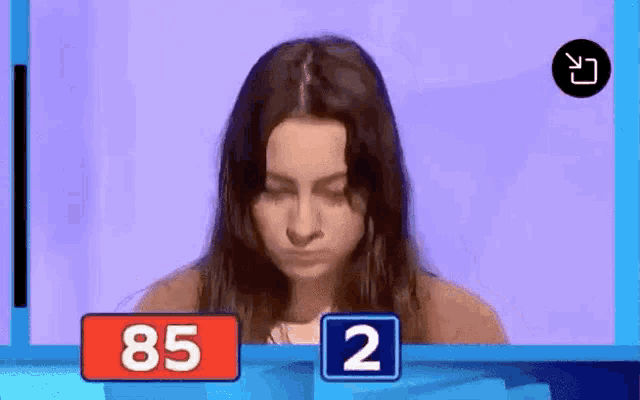 a woman is sitting in front of a screen with a sign that says 85 and a sign that says 2 .